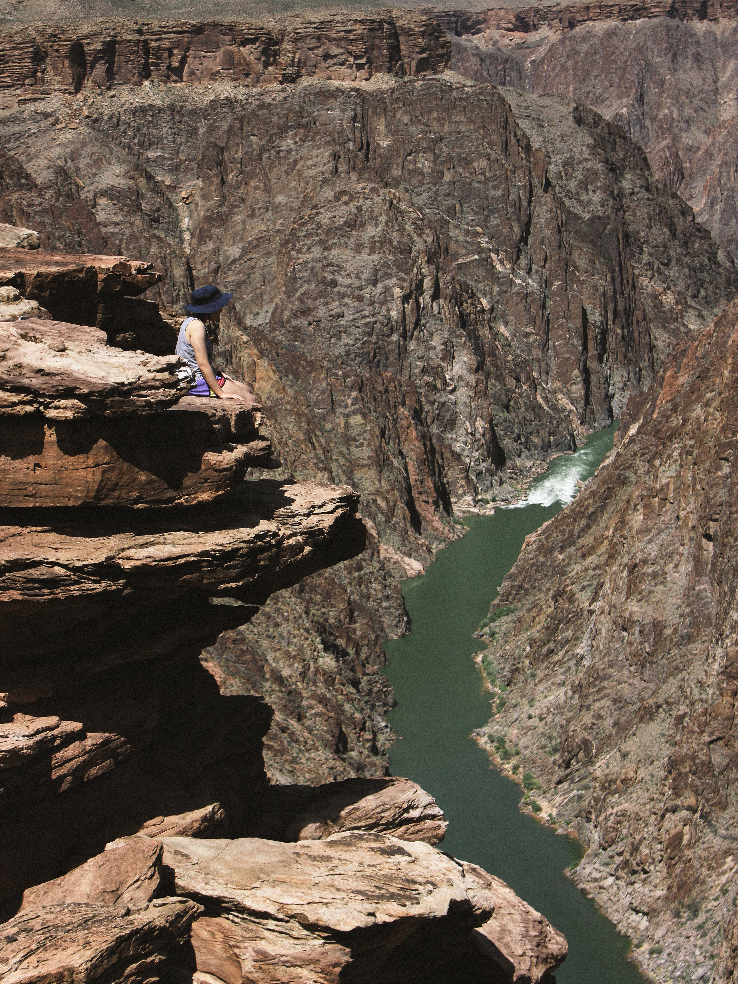 Vivian sitting at Plateau Point with the Colorado River beneath her.