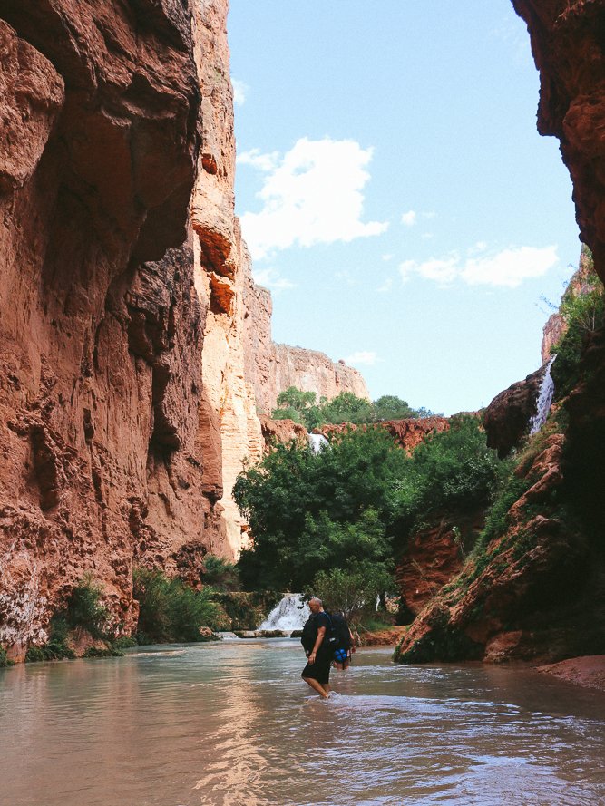 A man walking in a river by Mooney Falls area.