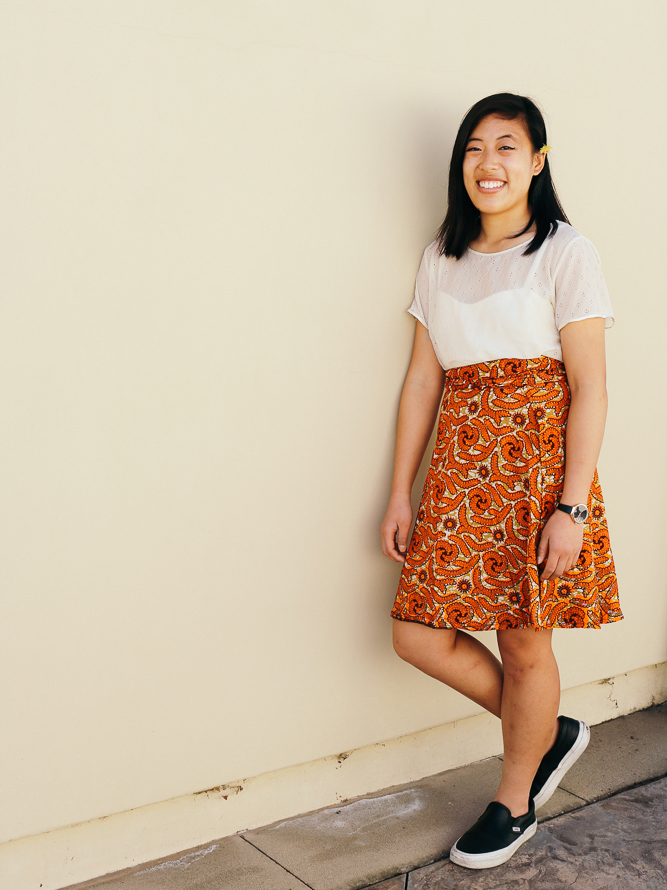 Vivian in a laced top, knee length wrap skirt, and leather sneakers.