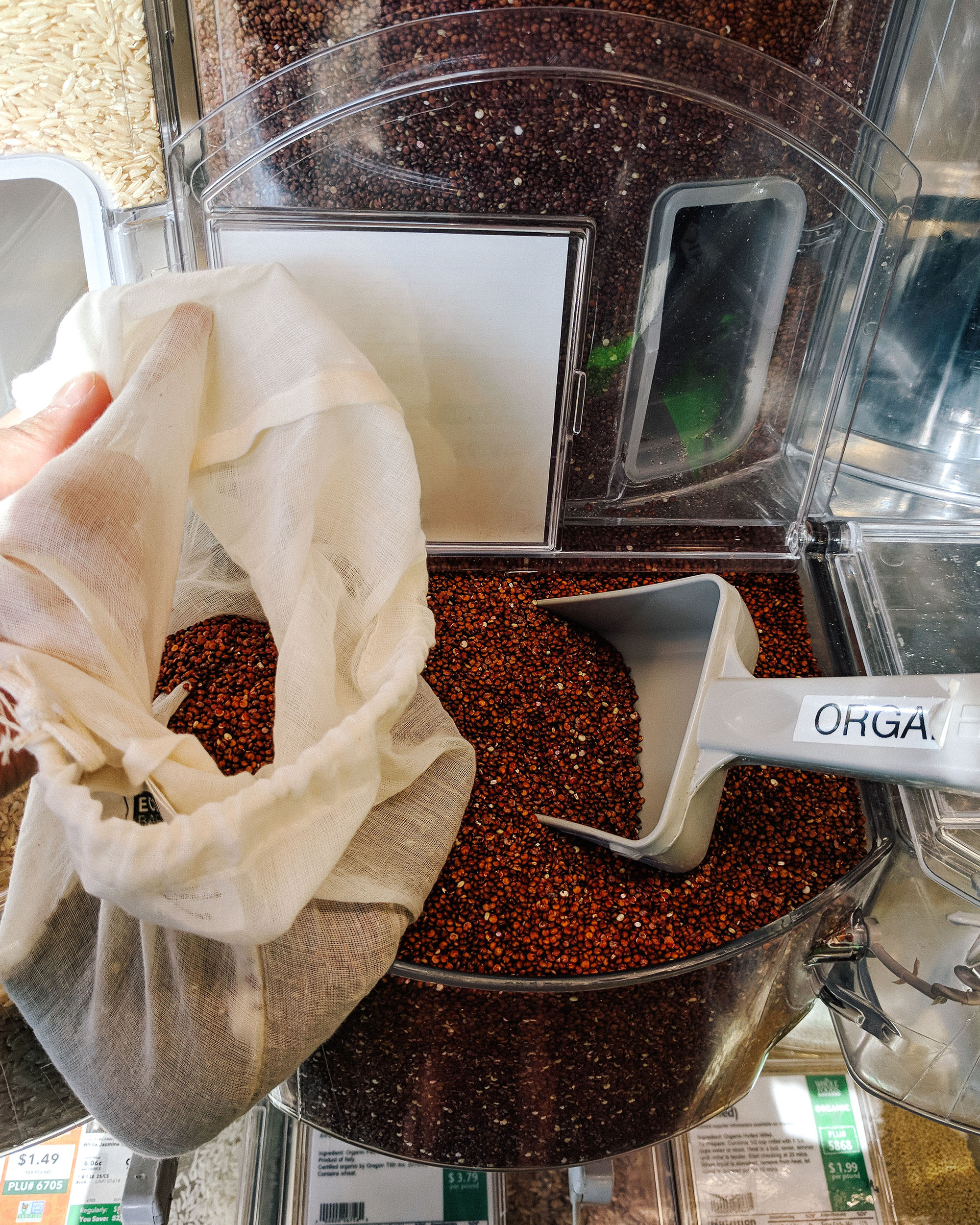Photo of a bulk bin filled with quinoa and in reusable produce bag